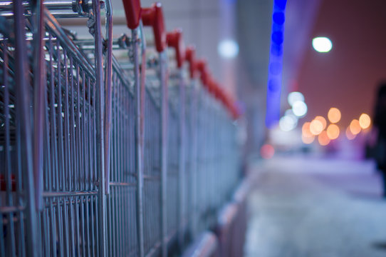 Row of shopping carts on winter street at evening near store