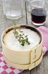 Mont d'Or cheese with red wine and thyme on red checked cloth
