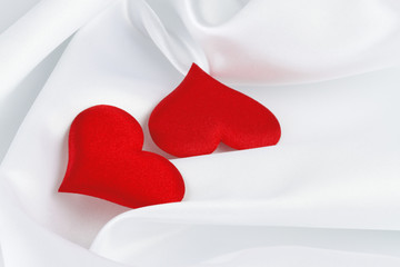 two red hearts on white silk