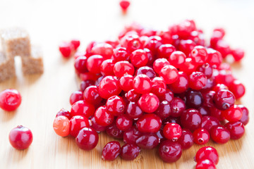 ripe cranberries and sugar on a wooden surface