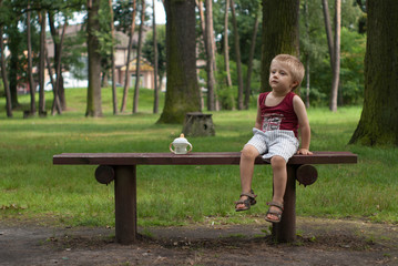 Boy sitting on a park bench with a bottle © serQ