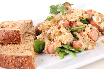 Scrambled eggs with frankfurters and spinach, and a fork