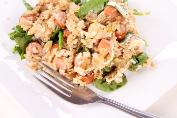 Scrambled eggs with frankfurters and spinach, and a fork