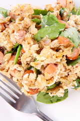 Scrambled eggs with frankfurters and spinach, and a fork