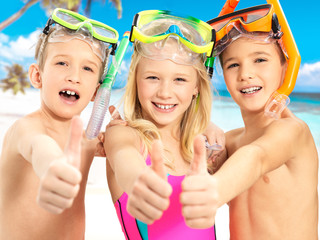 Happy children with thumbs-up gesture at beach