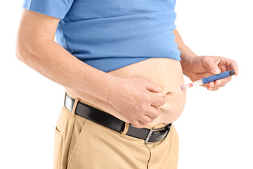 Mature man injecting insulin in his abdomen