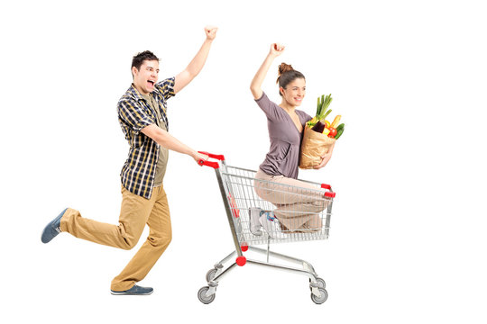 Young happy couple shopping, man pushing a shopping cart