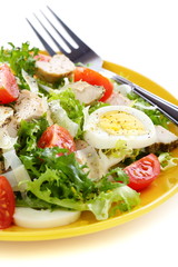 Salad with tomatoes, chicken and Parmesan cheese.