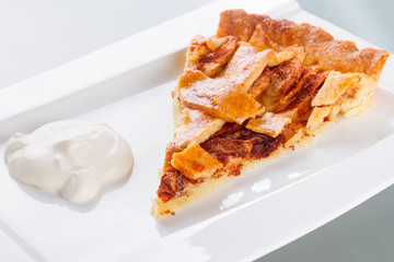 Piece of apple tart and cream on the plate