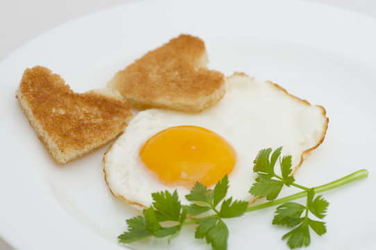 Fried egg with heart-shaped toasts for romantic breakfast