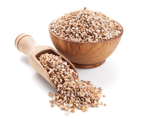 wheat groats in a wooden bowl isolated on white