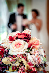 Beautiful bridal bouquet and bride and groom on background