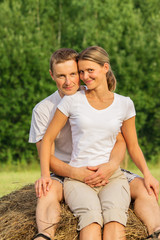 Young couple outdoors sit on hay