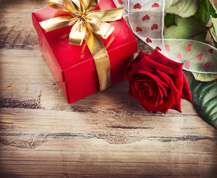 Valentine. Rose Flower and Gift Box over Wooden Background