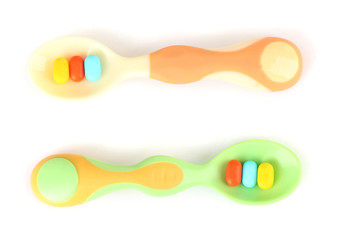 Plastic spoons with color pills, isolated on white