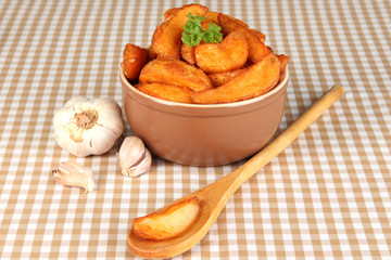 Appetizing village potatoes in bowl on beige tablecloth