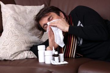 Kranker niest kräftig aus liegt auf Sofa, Medizin