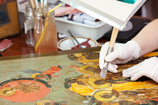 Restorer gilding on icon with agate burnisher