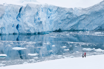 Deux touristes devant un mur de glace bleu glacier