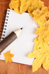 Colorful wooden pencil with autumn leafs on wooden table