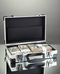 Suitcase with 100 dollar bills on grey background