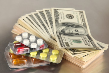 Pills and money on grey background