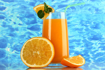 Glass of orange juice with mint and orange on sea background