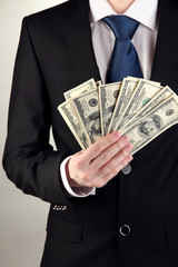 Business man holds lot of money on grey background