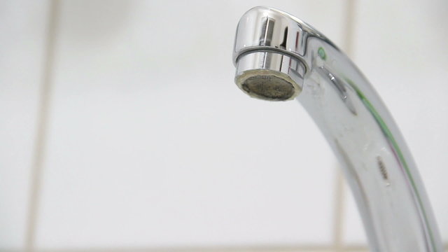 Tap water dripping down the sink, selective focus