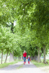 Fototapeta premium mother and her daughter with umbrellas in spring alley