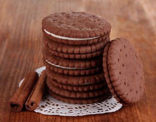 Chocolate cookies with creamy layer on wooden table close-up
