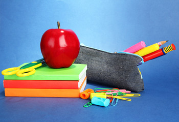 pencil box with school equipment on blue background