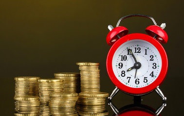 Alarm clock with coins on dark background