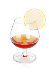 Glass of cognac with lemon on white