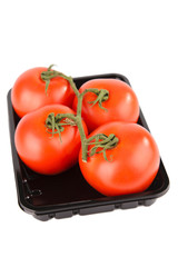 tomates en rama, en una bandeja negra sobre fondo blanco