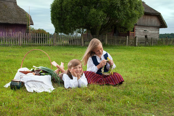 Little boy and girl sitting on a lawn in a national latvian clot