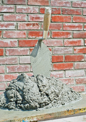 Bricklayers trowel and grout in fromnt of brick wall