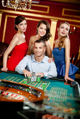 Man surrounded by girls gambles roulette at the casino - 48928148