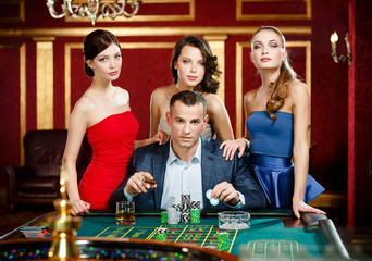Man surrounded by women gambles roulette at the gambling house