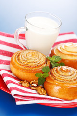 Three cinnamon rolls and jug of milk on red plate