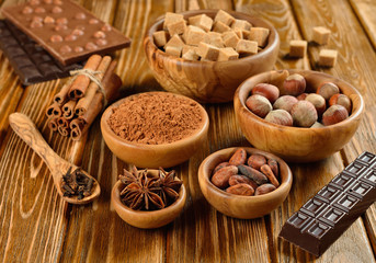 Fototapeta na wymiar Orzechy, przyprawy i kakao w drewnianej misce na brązowej tablicy