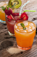 fresh fruit juices on wooden table, on green background