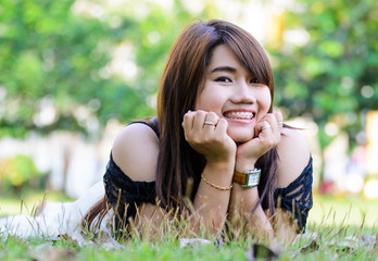 Beautiful Girl lying on the Field.Green Grass. Happy and Smiling