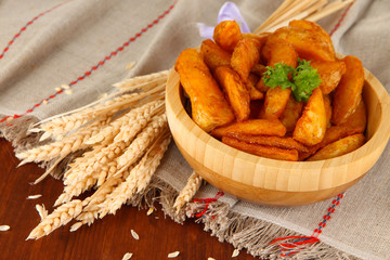 Appetizing village potatoes in bowl on wooden table close-up