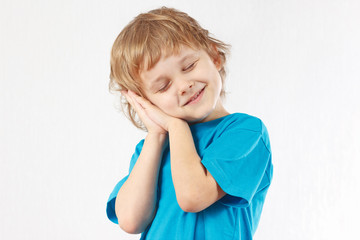 Little boy shows how he sleeps on a white background