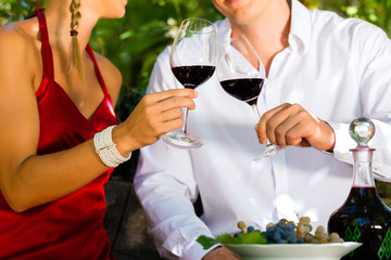 Woman and man in vineyard drinking wine