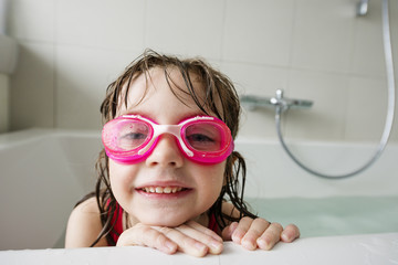 a happy  little girl with swim glasses bathing