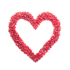 ripe pomegranate seeds in form of heart isolated on white backgr