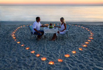 A young lovers couple share a romantic dinner with candles heart