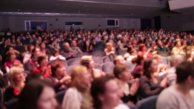 Defocused people applaud after the premiere.
